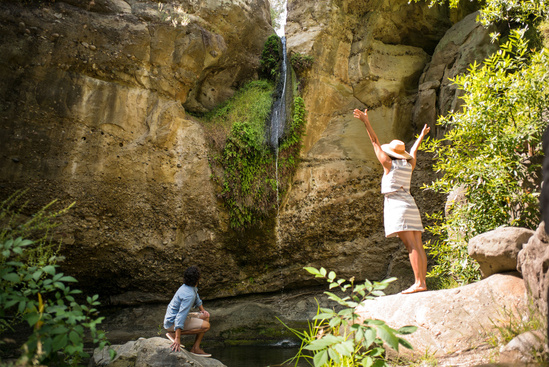 A couple enjoys a very small waterfall.