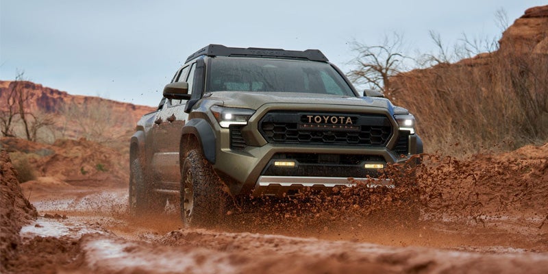 Front view of a Toyota Tacoma driving through mud
