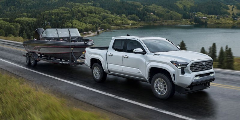 A white Toyota Tacoma pulls a boat down a hgihway